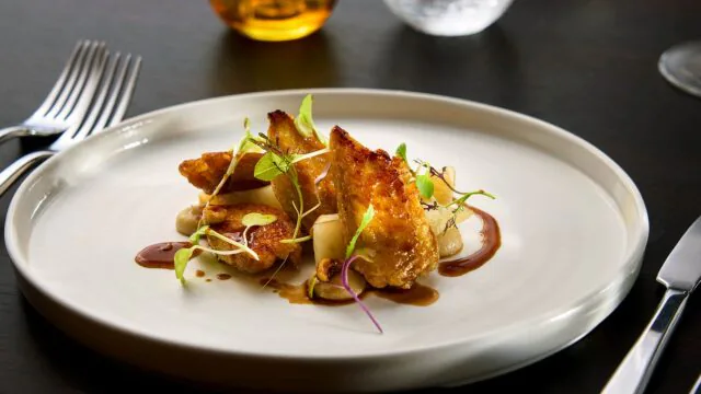 Elegant gourmet dish with crispy chicken, garnished with fresh herbs, perfect for a luxurious dining experience.