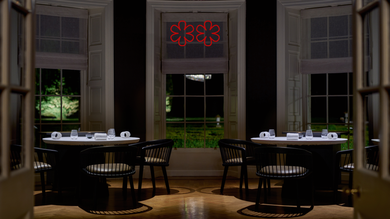 Elegant dining room with round tables, cosy seating, large windows, and a serene garden view, perfect for fine dining.