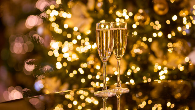 Two champagne flutes sparkling on a festive table with warm, soft bokeh lights, creating a cosy and elegant atmosphere.