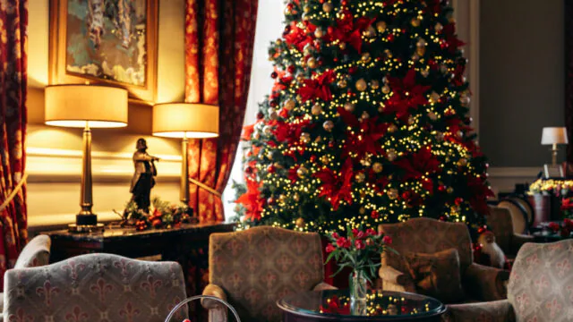 Elegant lounge with festive Christmas tree, plush chairs, and exquisite afternoon tea, creating a warm, inviting ambiance.