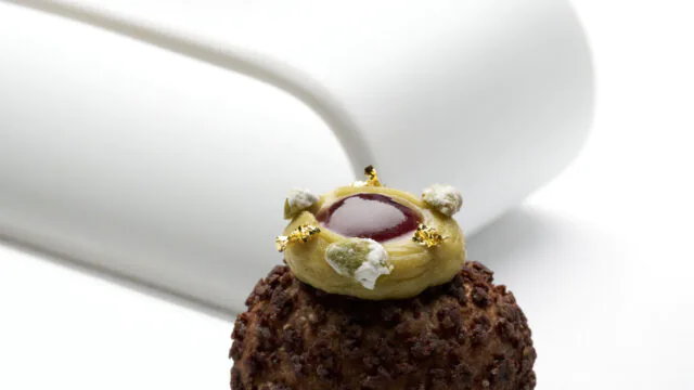 Luxurious chocolate pastry topped with gold and cream, showcasing gourmet dessert offerings at upscale hotel restaurant.