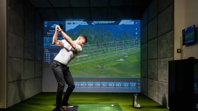 Guest enjoying state-of-the-art indoor golf simulator at luxury hotel, perfect for golf enthusiasts.