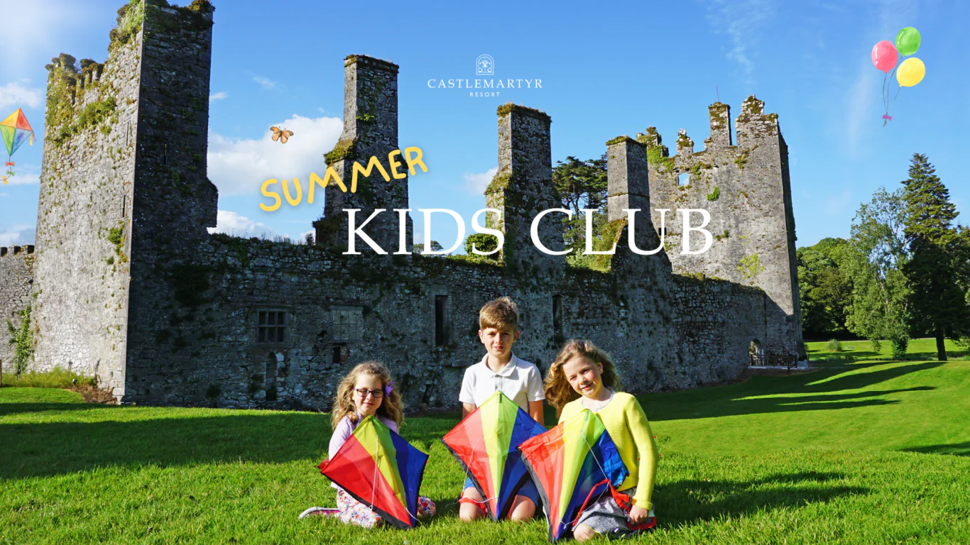 Children with kites enjoy outdoor fun by ancient castle ruins at Castlemartyr Resort's Summer Kids Club.